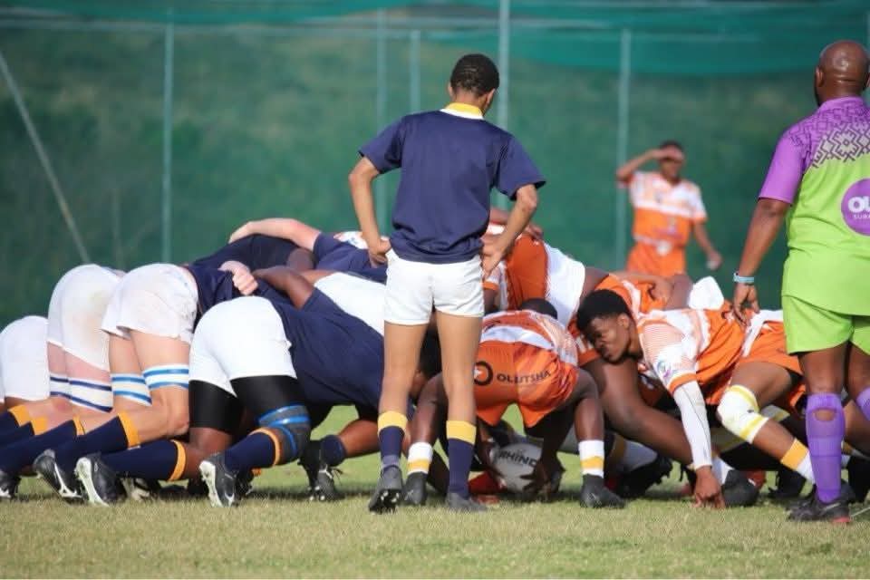 Academy front row packing down in a scrum against a navy-jerseyed side
