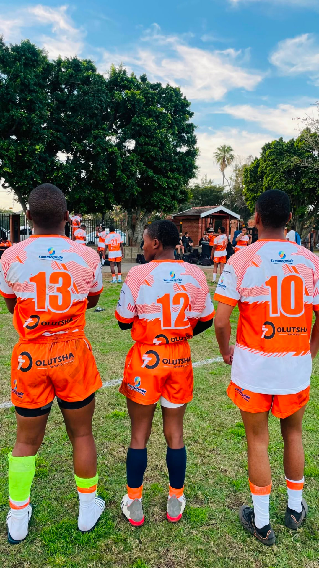 Academy backline players numbered 13, 12 and 10 watching from the touchline